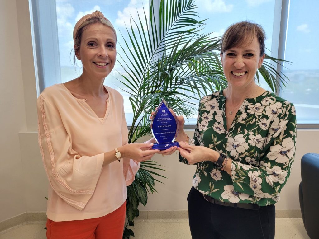 a woman handing another woman an award