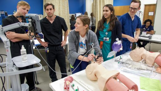 three people practicing with a cpr dummy