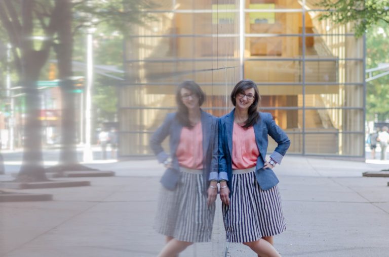 woman smiling, leaned against reflective wall