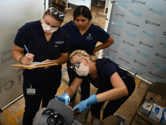 three dental health care providers work with a patient
