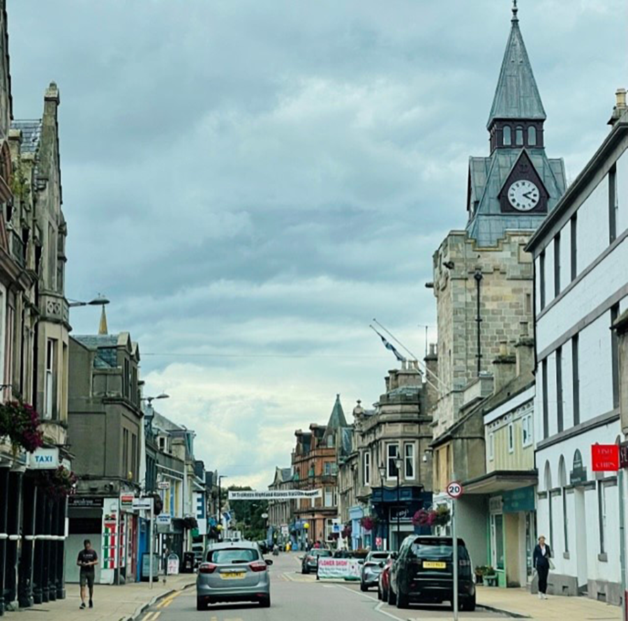 cars drive down a one-way street in a town in Scotland