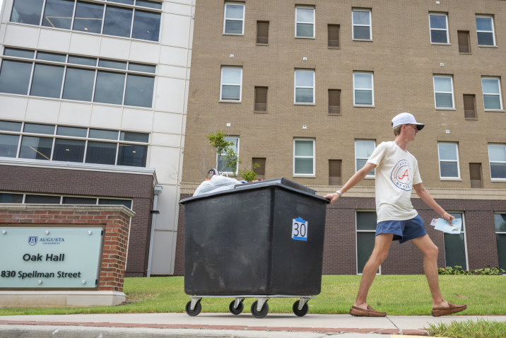man pulling a cart past the entrance of a residence hall
