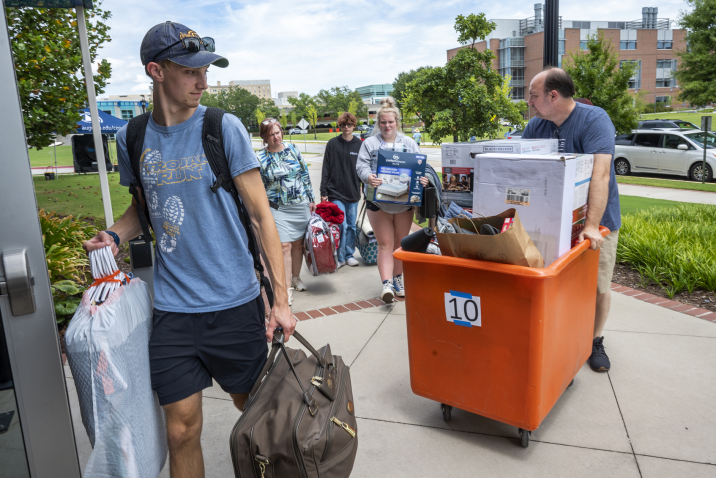 man and family carrying items into residence hall