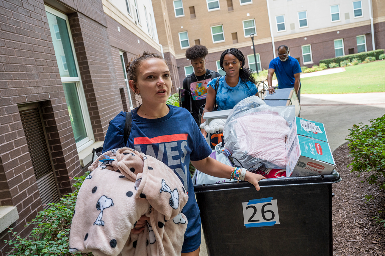 women and men with large carts moving into apartment