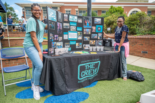 student smiling outside at a decorated table