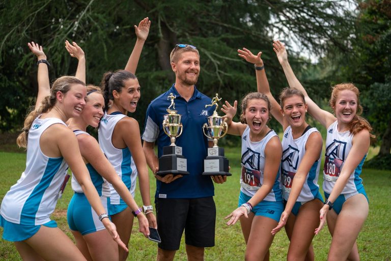 Women celebrating with man holding trophies