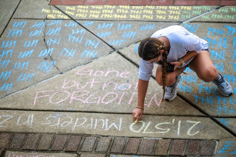 student uses chalk on the sidewalk