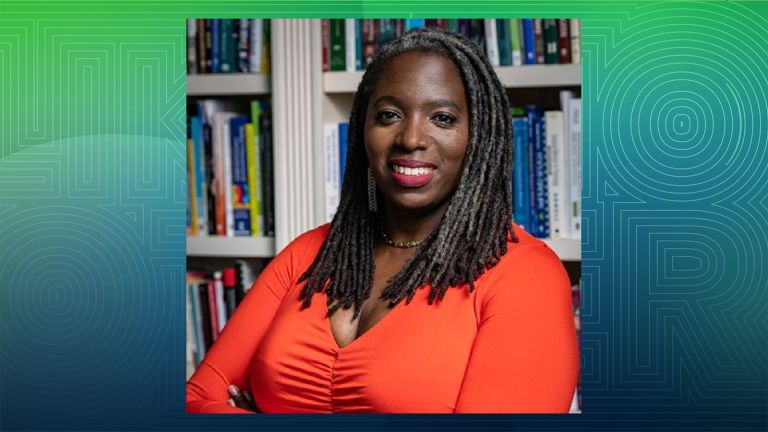 woman with arms crossed smiling in front of book shelf