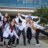 students in white coats in silly poses for photo