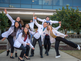 students in white coats in silly poses for photo