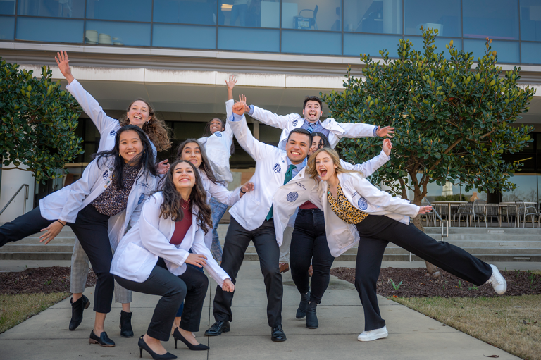 students in white coats in silly poses for photo