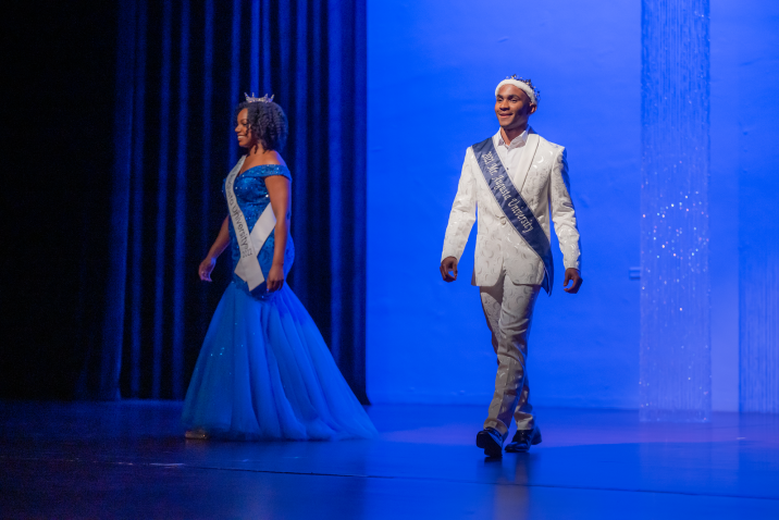 people in sashes walk on stage