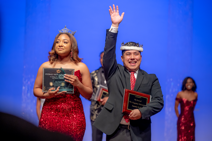man and woman with awards and wearing a crown at a scholarship competition