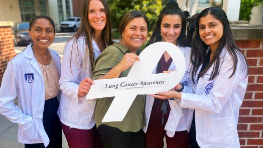Five women holding a white ribbon to represent lung cancer awareness
