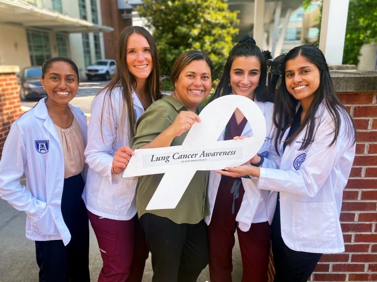 Five women holding a white ribbon to represent lung cancer awareness