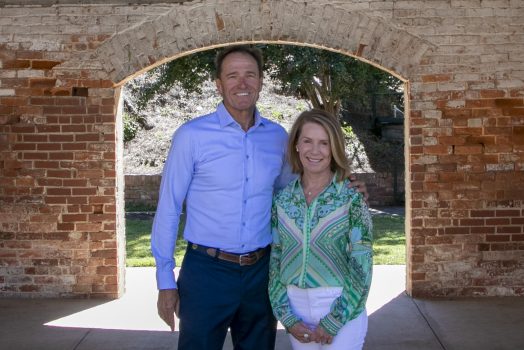 two people standing outdoors near a brick archway