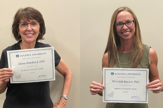 two women holding paper awards