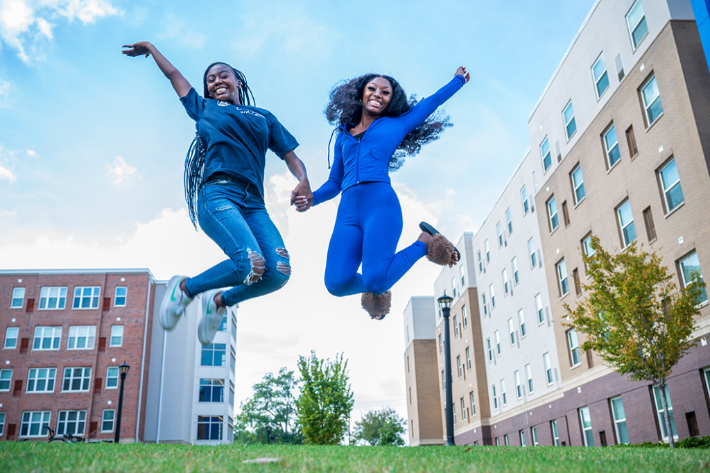 two women jump outside while smiling