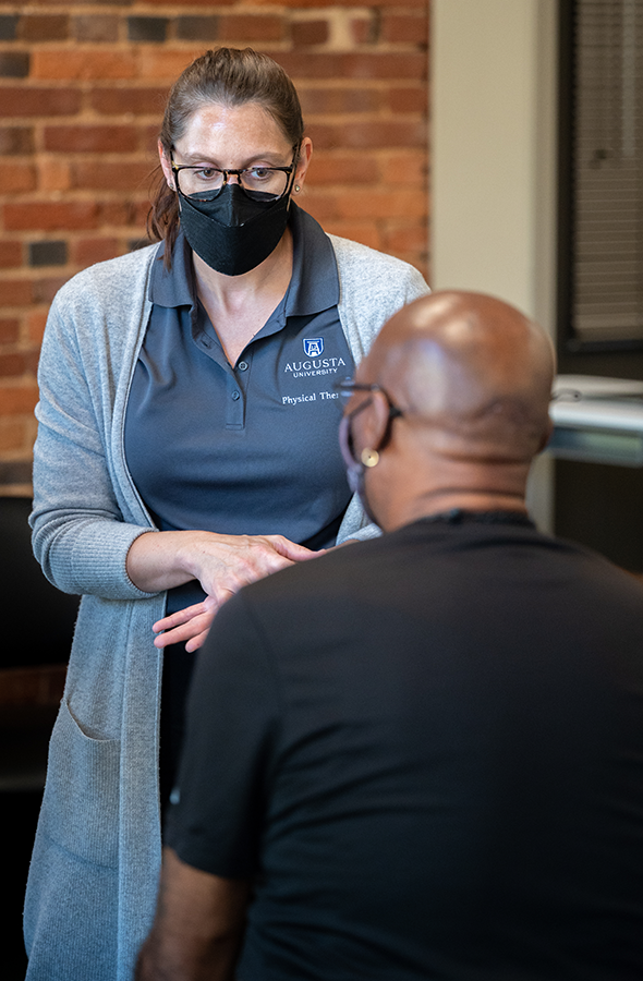 A doctor wearing a mask talking to a patient