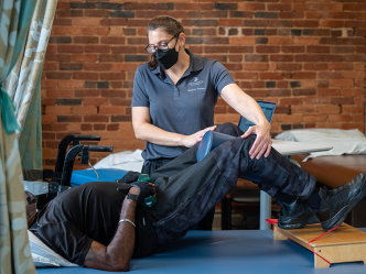 woman physical therapist and male patient practicing exercises
