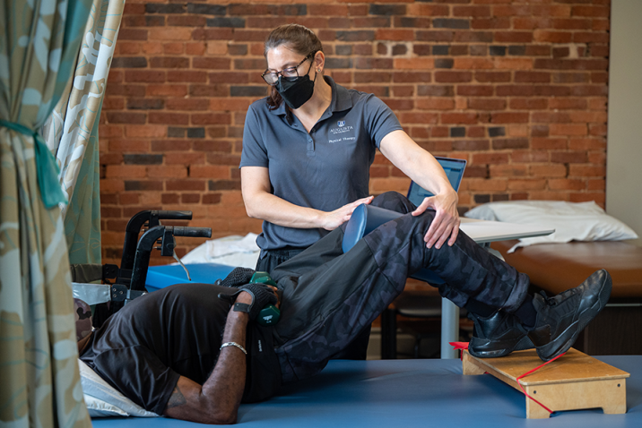 woman physical therapist and male patient practicing exercises