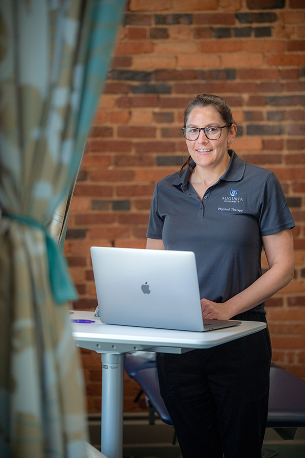 woman standing behind tall table with laptop