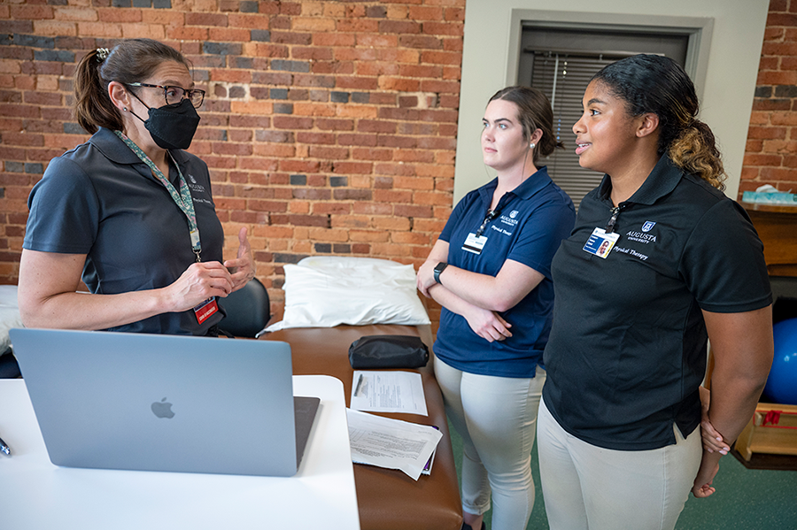 woman wearing mask talks with two female students