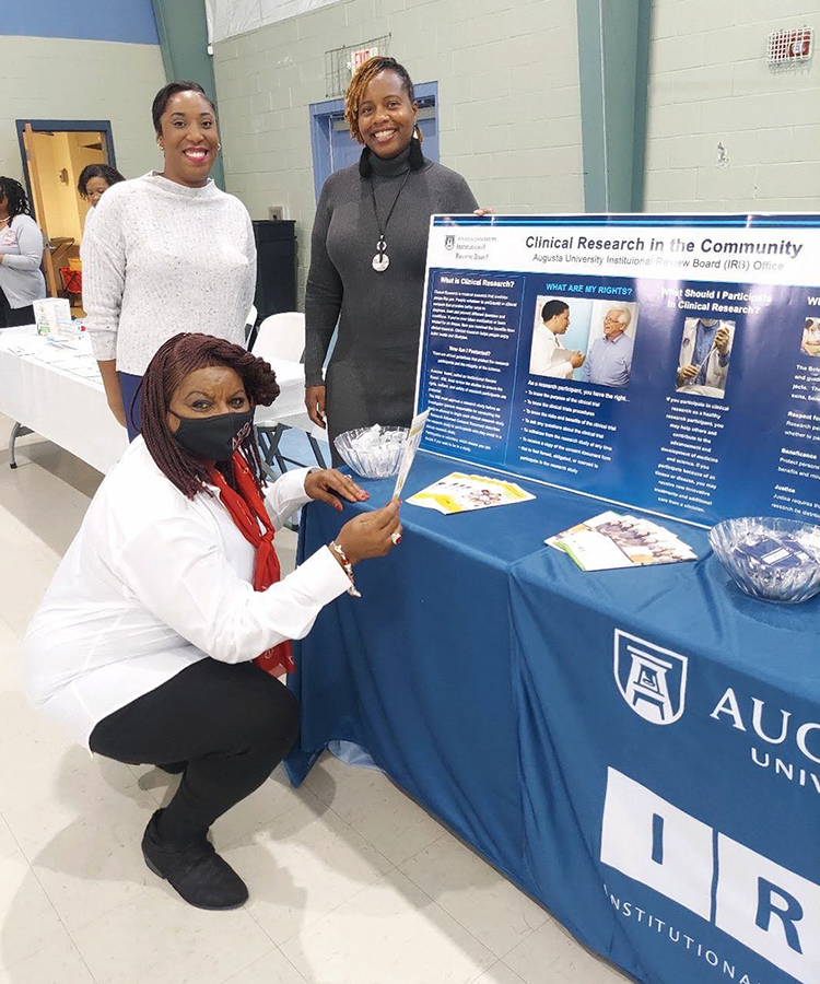 three women pose for a photo in front of a table with a chart 