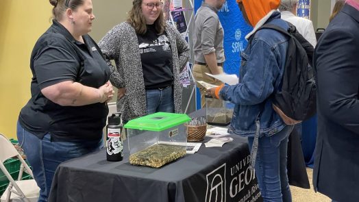 Two women talking to a student at job fair