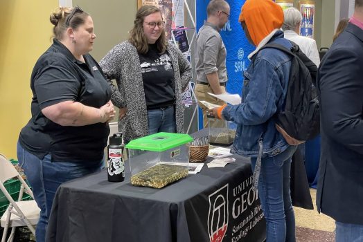 Two women talking to a student at job fair