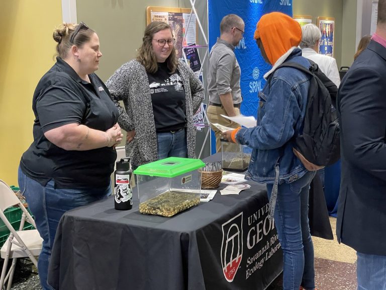 Two women talking to a student at job fair