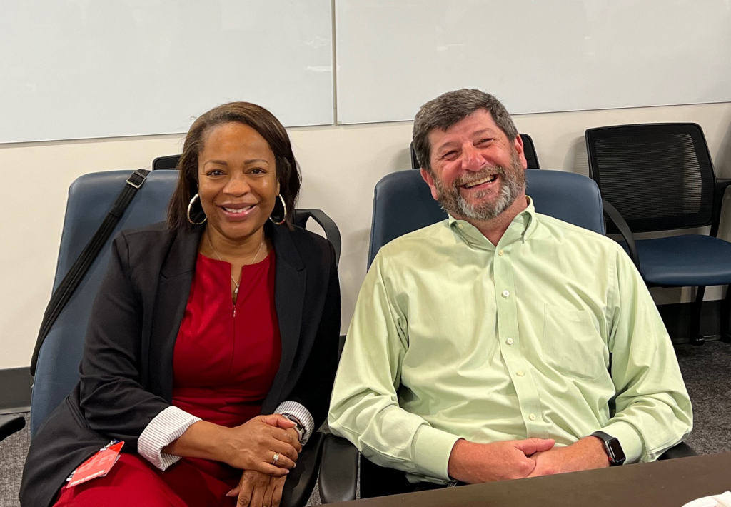 woman and man smiling in a conference room