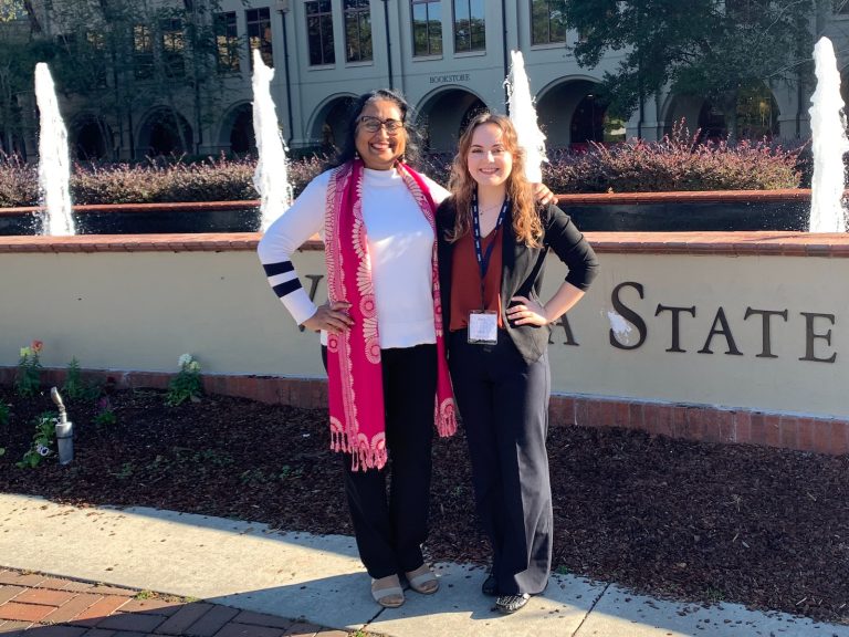 two women standing outside a university's entrance
