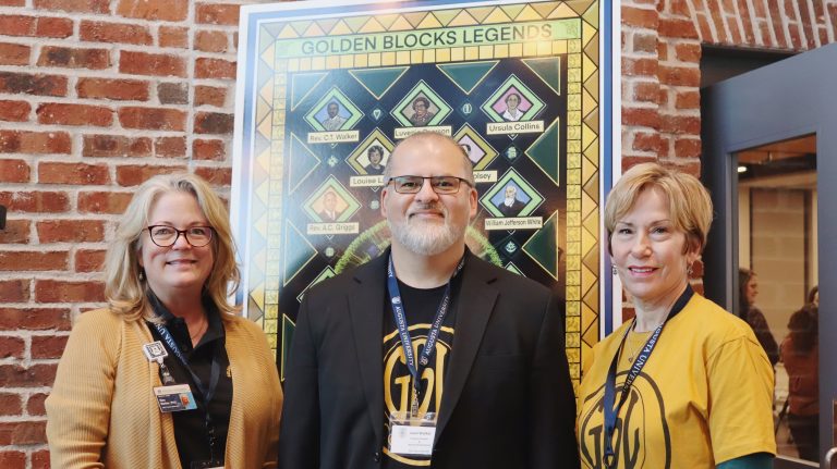 two women and man stand together