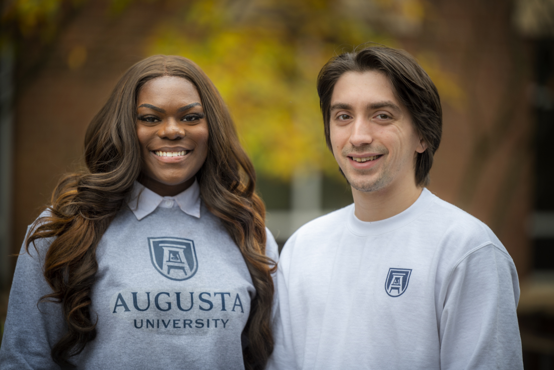 woman and man smiling outdoors, both wearing Augusta University shirts