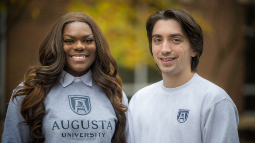woman and man smiling outdoors, both wearing Augusta University shirts