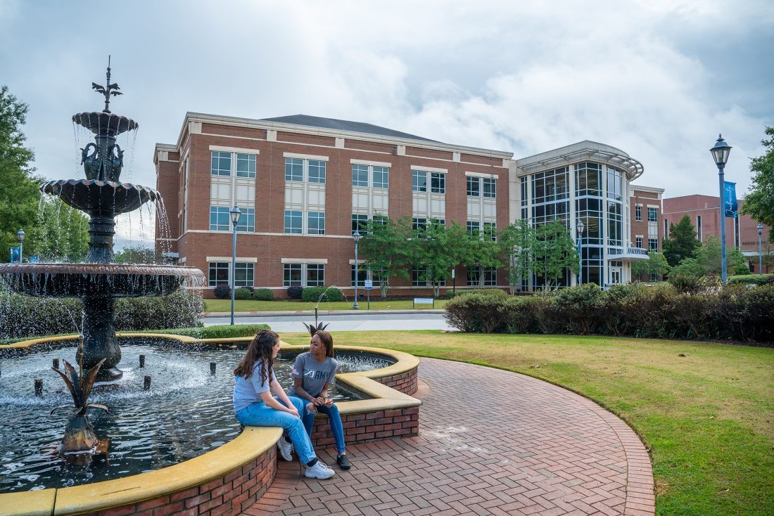 Two people sitting by a fountain on a college campus