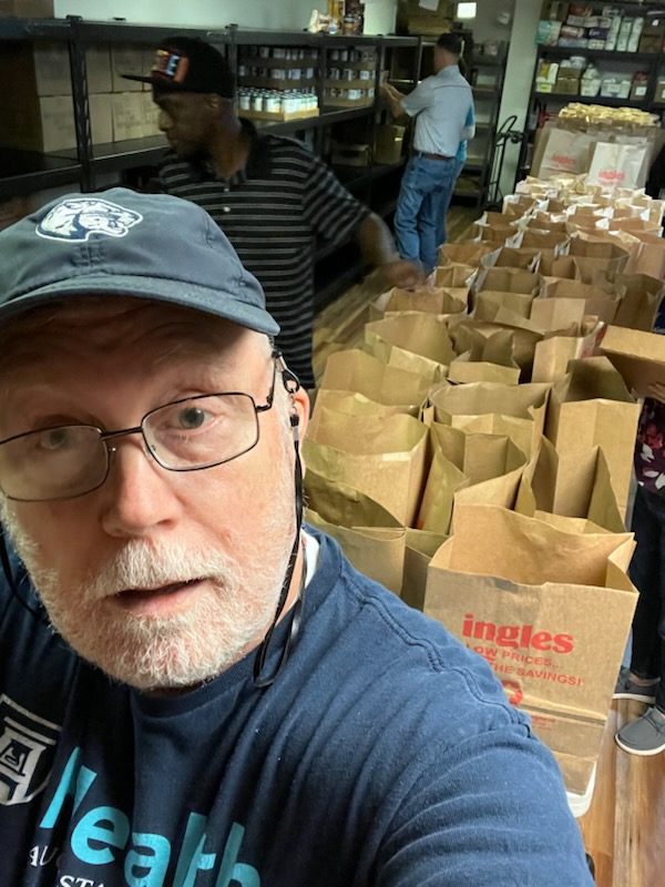 Man standing in front of a table filled with bags of food during Days of Service event
