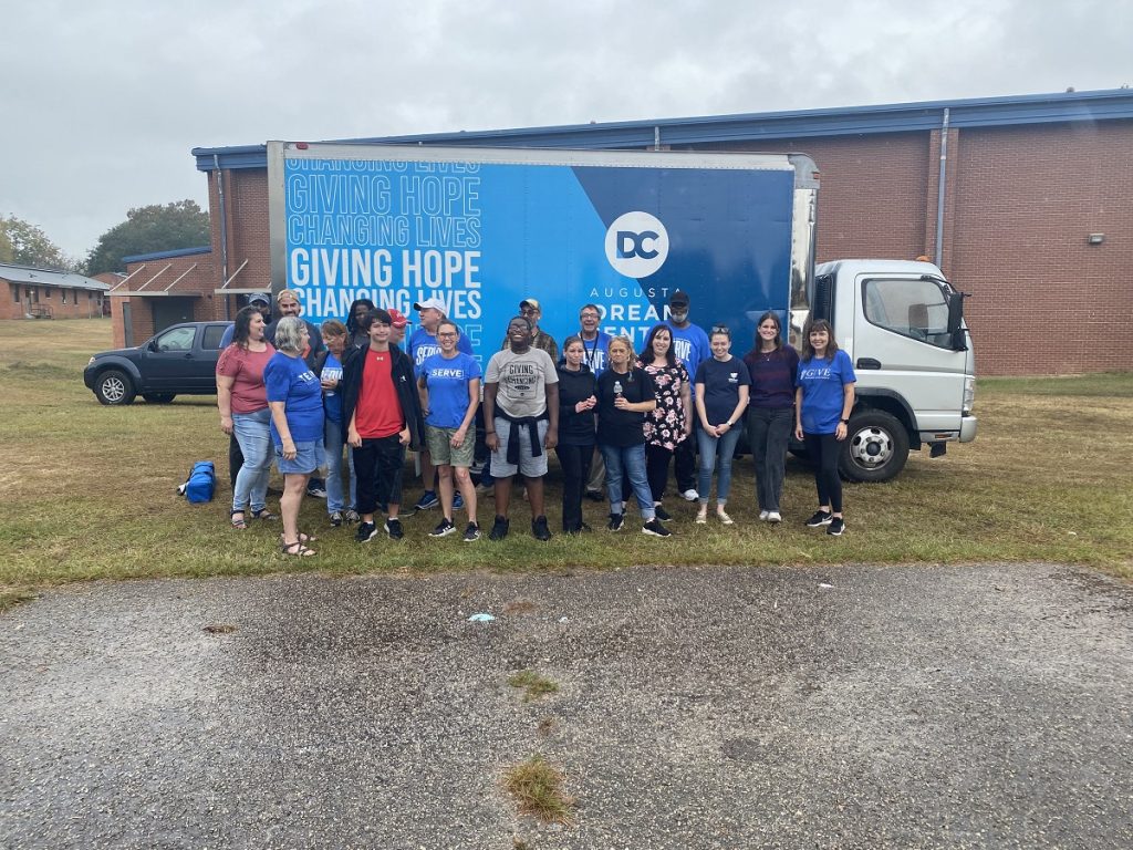 Men and  women standing in front of a truck
