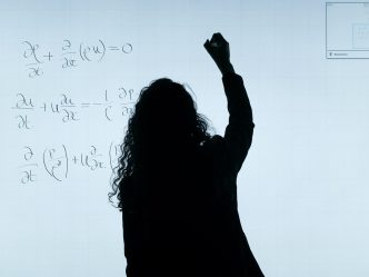 Woman doing calculations on a white board
