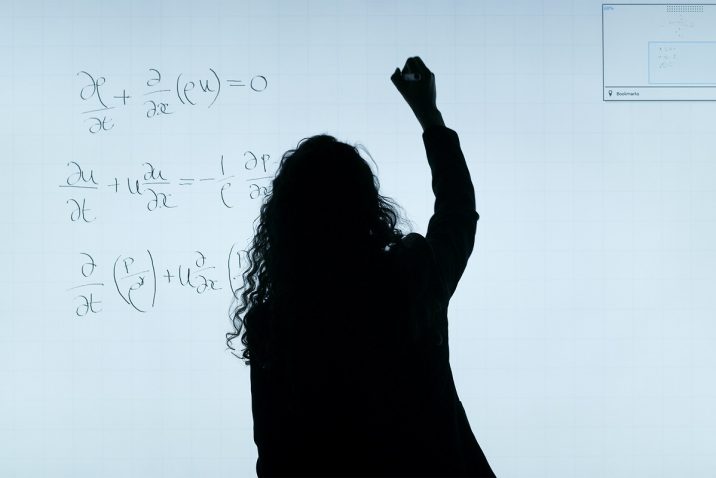 Woman doing calculations on a white board