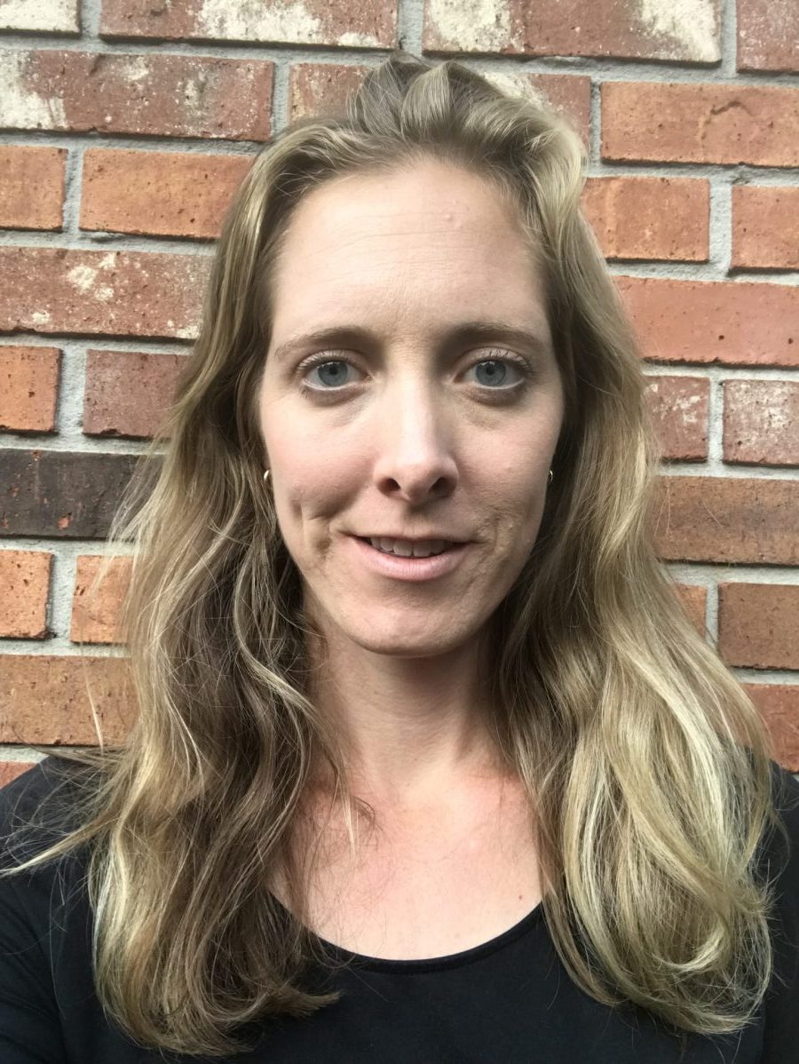 blonde woman standing against brick wall