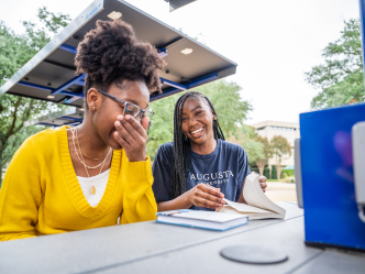 two women reading a book and laughing