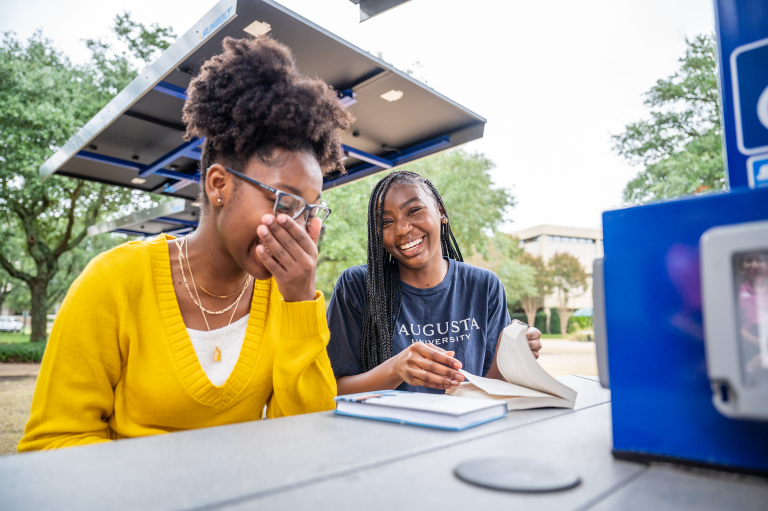 two women reading a book and laughing
