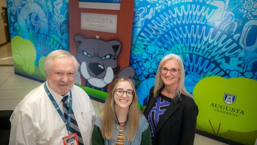 three people standing by a mural