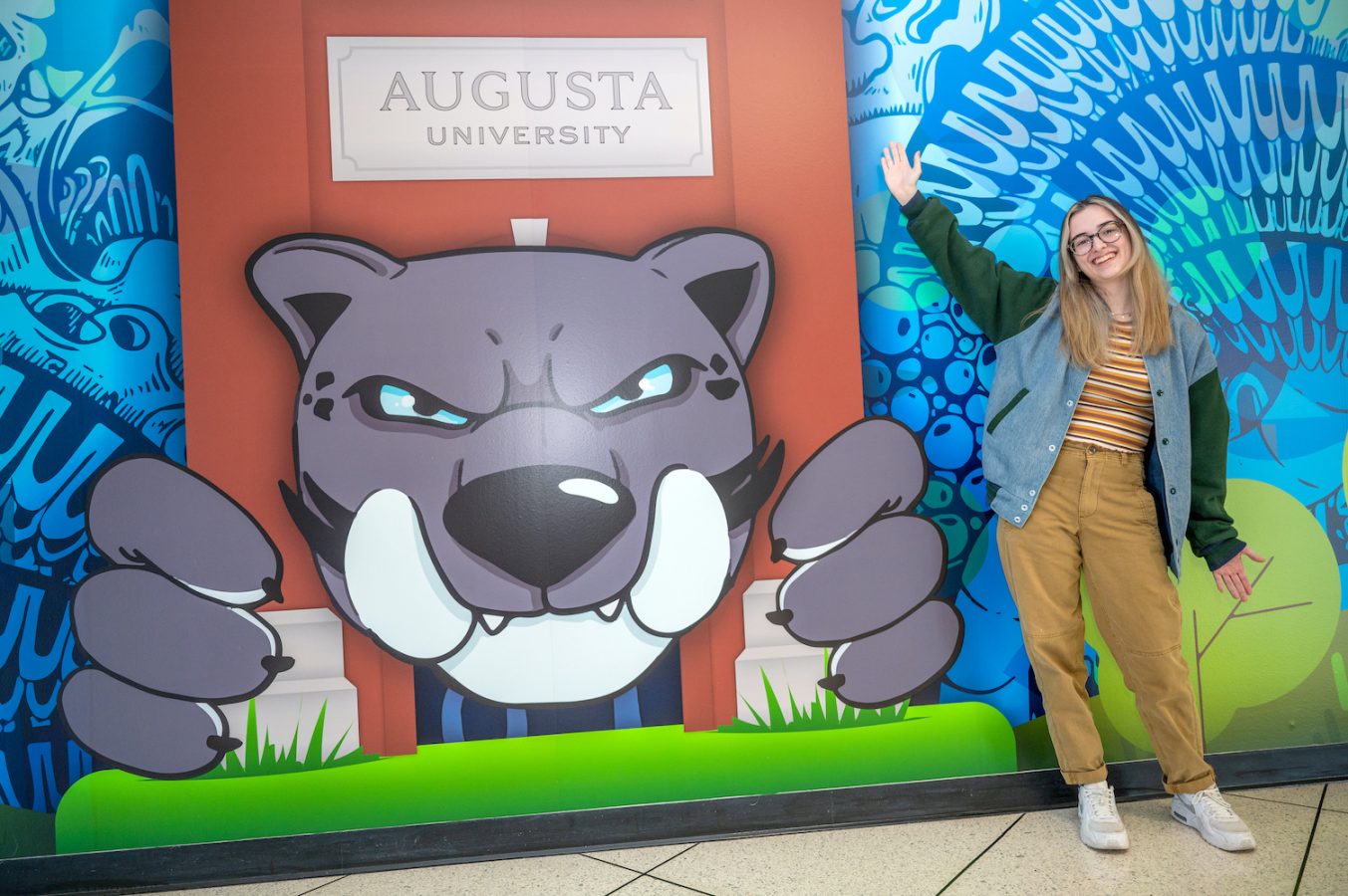 Student standing in front of a mural.