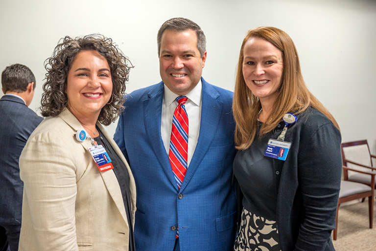 two women and a man smile at a camera