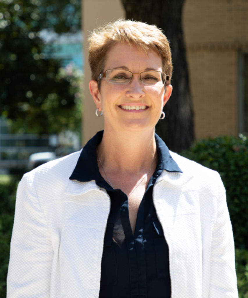 Woman wearing glasses and a white lab coat smiles