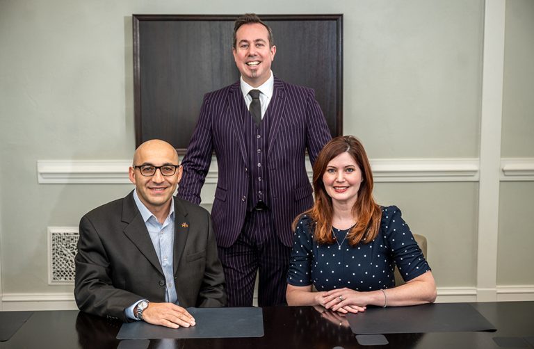 Man standing behind man and woman sitting