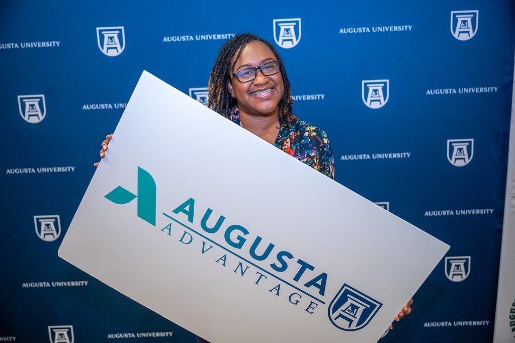 Woman holding sign with Augusta Advantage logo